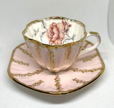 a pink and gold tea cup on a saucer