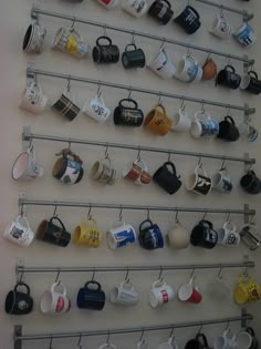 coffee cups are hanging on the wall and mugs are lined up in different colors