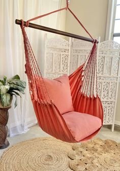 an orange hammock chair hanging from the ceiling in front of a white wall