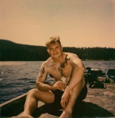 a shirtless man sitting on the edge of a boat