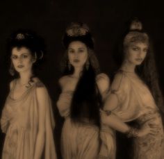 three beautiful women dressed in ancient greek costumes, one with long hair and the other with veils on her head