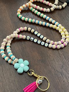 a wooden beaded necklace with a pink tassel and flower charm hanging from it