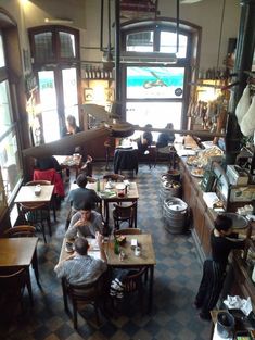 people sitting at tables in a restaurant with lots of food on the counters and windows