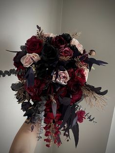 a woman holding a bouquet of red and black flowers