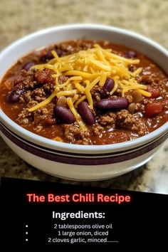 a bowl filled with chili and cheese on top of a granite counter next to a sign