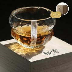 a glass bowl sitting on top of a wooden block with a label that reads,