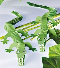 green paper cut out of alligators on top of leaves and stems with eyes in the middle