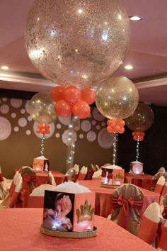 balloons are hanging from the ceiling above a table with an image on it and other decorations