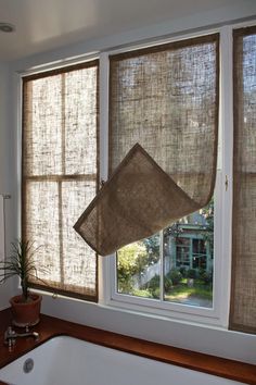 a bath tub sitting next to a window covered in burlaps and hanging from the ceiling