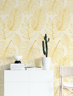 a white dresser sitting next to a wall with a plant on it's side