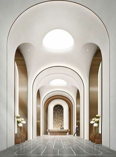 an empty hallway with arches and white walls is shown in this image, there are vases on either side of the doorway