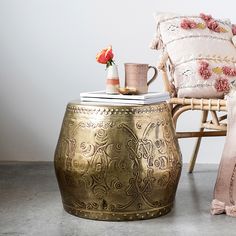 a chair and table with pillows on it next to each other in front of a white wall