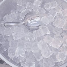 an ice bucket filled with lots of ice and a metal spoon on top of it