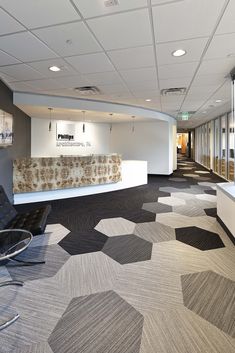 an office with carpeted flooring and large windows in the center, along with a black leather chair