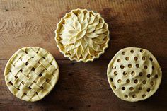 three pies sitting on top of a wooden table next to each other with holes in them