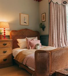 a bed sitting next to a window with curtains on top of it and a stuffed animal in the middle