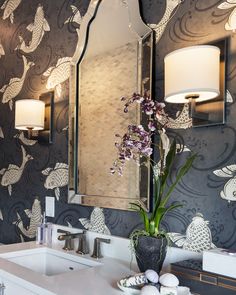 a bathroom sink with a mirror above it and flowers in a vase on the counter