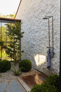 the outside of a house with stone walls and trees in front of it, along with gravel walkways