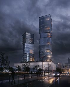 two tall buildings sitting next to each other on a wet street in the city at night