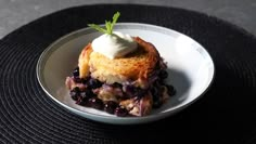 a small piece of cake with blueberries and whipped cream on top sits on a plate