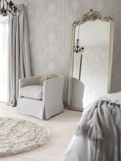 a white chair sitting in front of a large mirror