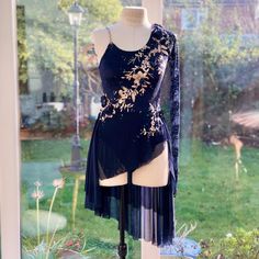 a mannequin wearing a dress on display in front of a window with grass and flowers