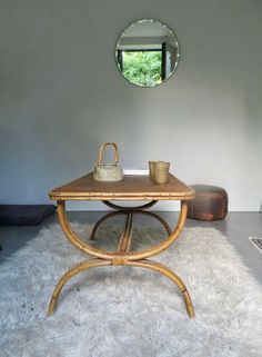 a table with a mirror on the wall above it and a rug in front of it