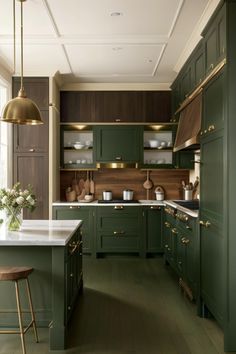 a kitchen with dark green cabinets and gold trim on the ceiling, along with wooden stools