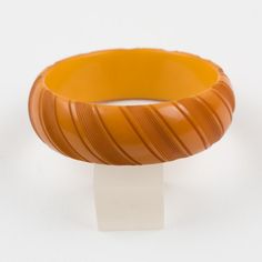 This is part of Chairish’s Costume Jewelry assortment.  This adorable butterscotch Bakelite bracelet bangle boasts a chunky domed shape with deep geometric carving and an intense butterscotch yellow/orange color.  Measurements: Inside across is 2.63 in diameter (6.6 cm) - outside across is 3.19 in diameter (8.1 cm) - width is 0.94 in wide (2.3 cm).  Please see the measurements noted above in the description for the best approximate dimensions. Cheap Orange Bangle Bracelet, Elegant Bakelite Bracelet Jewelry, Retro Yellow Bangle Bracelets, Elegant Bakelite Bracelet, Vintage Orange Bangle Bracelets, Gucci Bracelet, Chanel Bracelet, Bakelite Bracelets, 18k Gold Bracelet