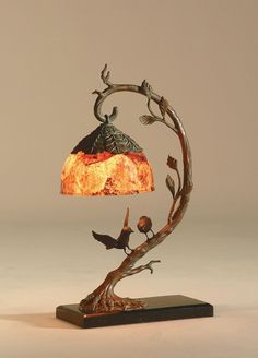 a lamp that is sitting on top of a wooden base and has birds perched on it