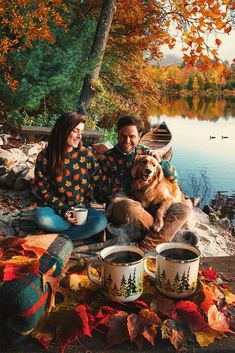 a man and woman sitting on the ground with their dog next to two cups of coffee