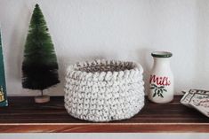 a crocheted basket sitting on top of a wooden shelf