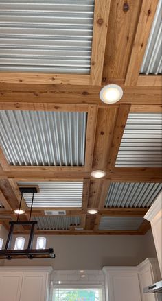 a kitchen with white cabinets and wooden ceilinging in the center is an overhead light