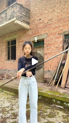 a woman standing in front of a brick building holding a baseball bat and looking at the camera