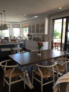 a dining room table and chairs in front of an open kitchen with sliding glass doors