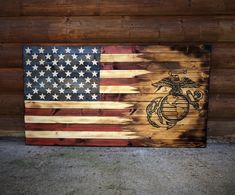 an american flag with the us marine emblem on it is displayed in front of a wooden wall