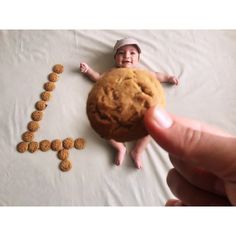 a person holding a cookie in front of a photo of a baby on the floor