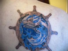 the back of a man's shoulder with a ship wheel tattoo design on it