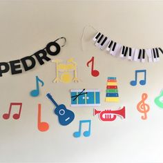 paper cutouts with musical instruments and name on them are hanging from the wall in front of a white background