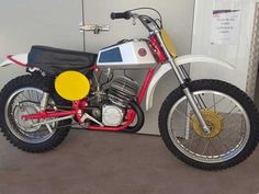 a red and white dirt bike parked next to a wall