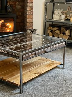 a glass table sitting in front of a fire place with logs on the floor next to it