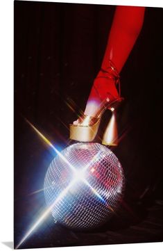 a woman's feet in high heels on top of a disco ball with lights