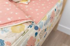 an unmade bed with pink and blue floral bedspread