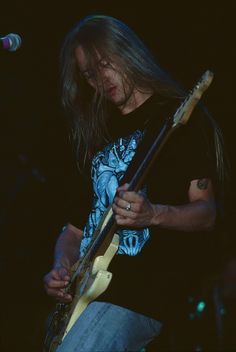 a man with long hair playing a guitar