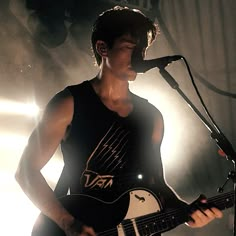 a young man playing an electric guitar in front of a microphone