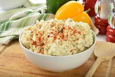 a white bowl filled with mashed potatoes on top of a wooden cutting board