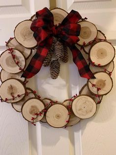 a wreath made out of wood slices with a pine cone and red berries on it