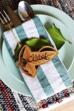 a plate with a fork, knife and spoon on it next to a green leaf