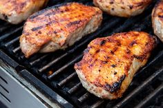 several pieces of meat cooking on a grill