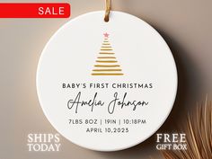 a baby's first christmas ornament hanging on a wall next to palm leaves